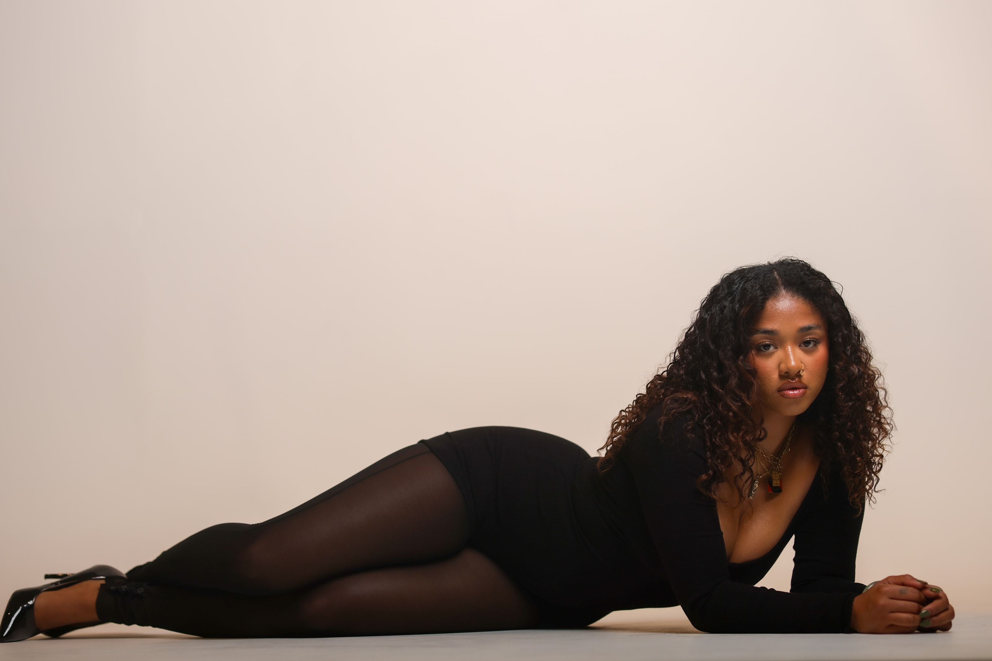 Halley reclining on the studio floor, propped on one arm, looking directly into the lens