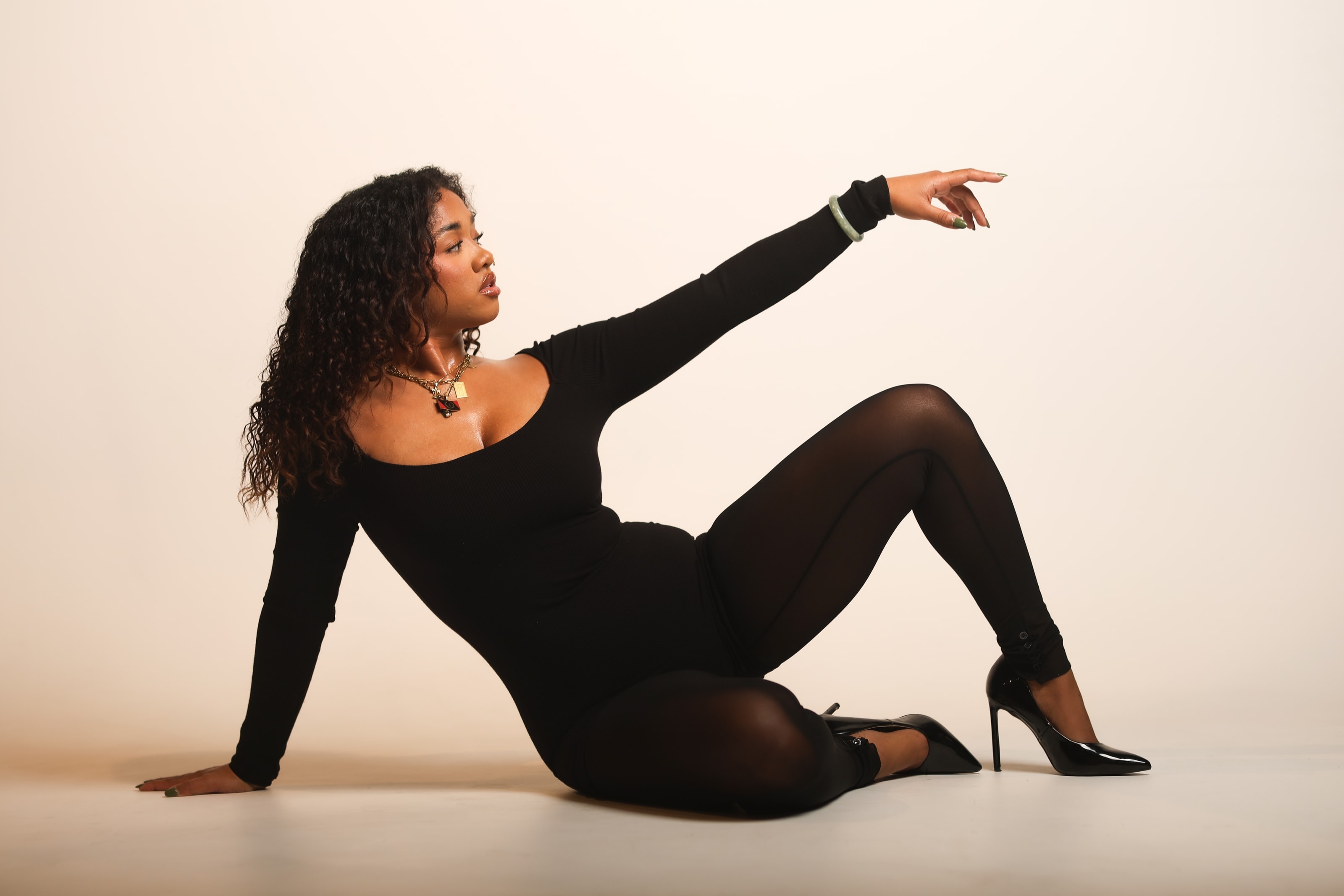 Halley reclining on the studio floor in a black bodysuit, one arm raised overhead